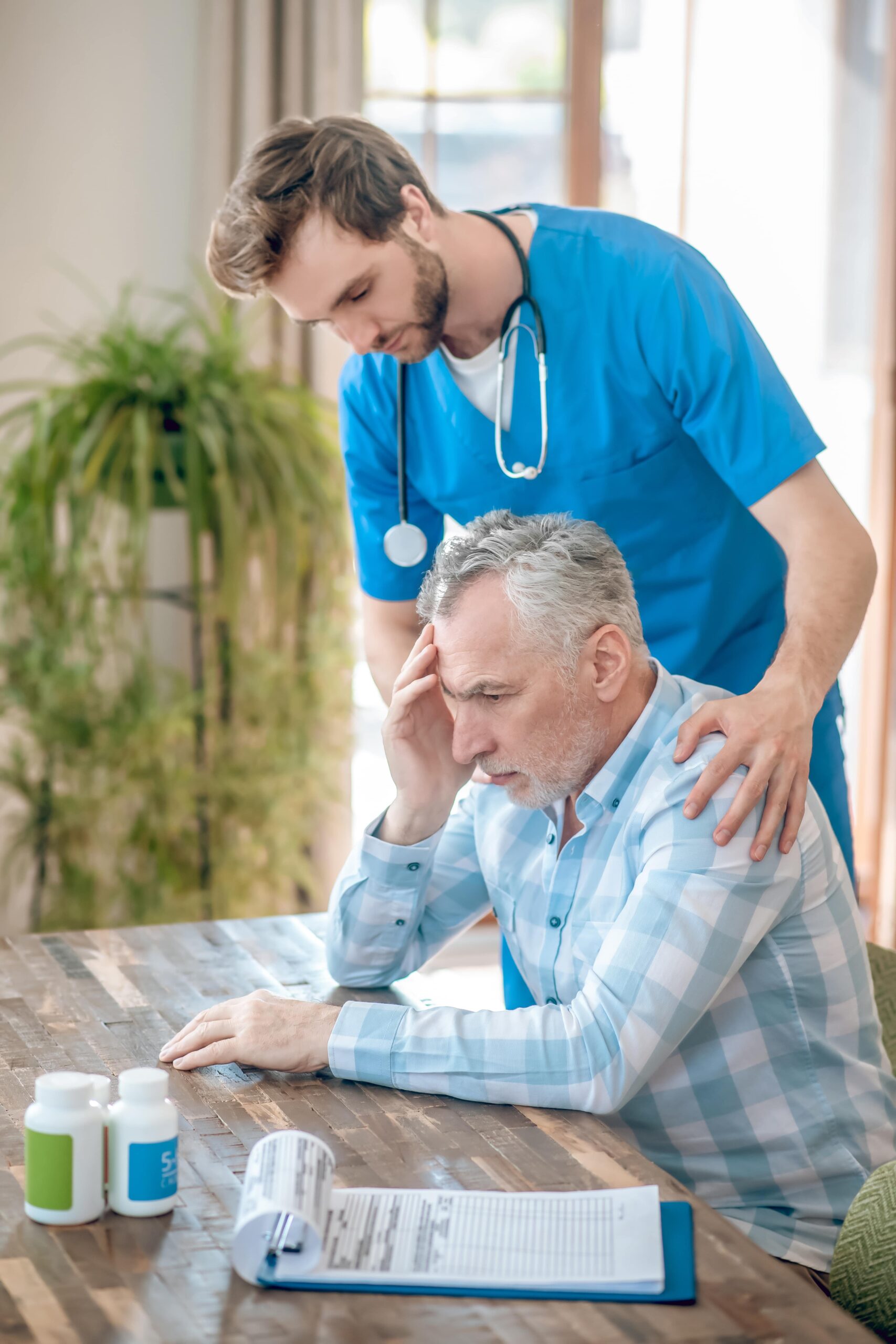 Older man with pain and nurse assisting